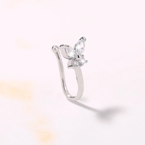 Macro detail of a silver butterfly nose clip featuring sparkling zircon stones on marble