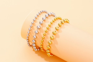 Detail of minimalist gold and silver hollow bead bracelets on a cylindrical stand