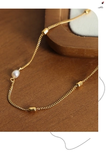 Detailed macro view of 18k gold-plated titanium chain with a freshwater pearl and bead