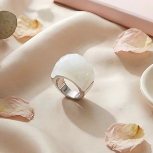 Detailed view of faceted white crystal ring with 18k gold plating on soft silk fabric