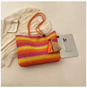 Flat lay of pink and orange striped straw tote bag with tassels for beach vacations