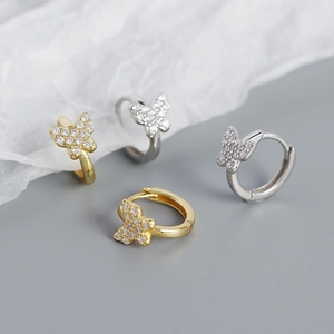 Close-up of butterfly hoop earrings in gold and silver finish with sparkling zircons