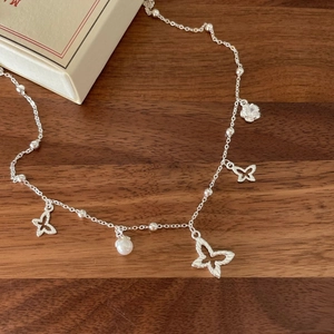 Minimalist 925 sterling silver golden butterfly necklace with a white pearl on wood