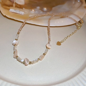 Detail of necklace with champagne beads and irregular shell stones on ceramic plate