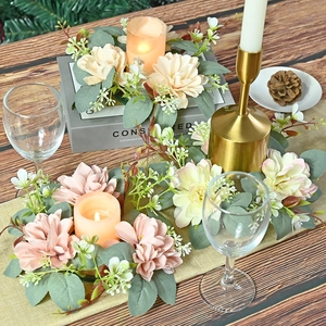 Artificial dahlia wreath candle ring with pink flowers and eucalyptus leaves on wooden table