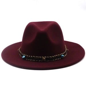 Detail of burgundy fedora hat with woven band featuring gold studs and turquoise stone