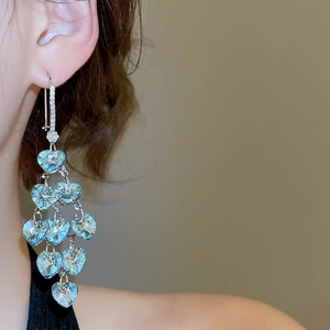 Detail of light blue heart crystal tassel earrings worn on a model showing dangle length