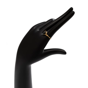 Macro detail of handmade wire-wrapped golden ring featuring a black heart-shaped gemstone