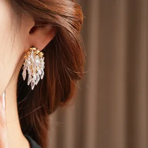 Boucles d'oreilles dorées avec pampilles en cristal marquise sur un mannequin