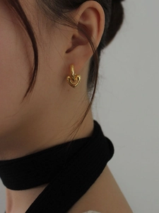 Close-up of golden heart-shaped nested earrings worn by a model in a side view