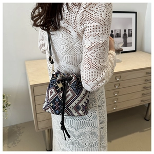 Ethnic bucket bag with geometric patterns shown on model in white lace dress