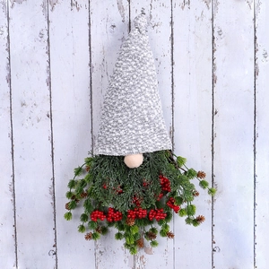 Couronne de gnome de Noël avec baies rouges et pommes de pin sur mur en bois