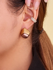 Close-up of a geometric gold pearl stud earring and crystal ear cuff on a female model