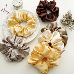 Detailed view of assorted satin scrunchies in earth tones arranged on a vintage tray