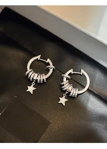 Close-up of silver zircon star drop earrings on a black leather surface background