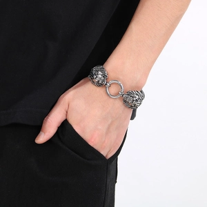 Detail of silver lion head leather bracelet on male model wrist with metal ring clasp