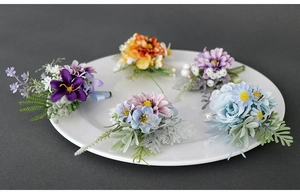 Detailed close-up of artificial flower boutonnieres with silk petals and satin ribbon wrap