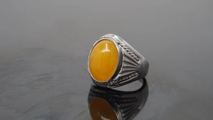 Macro shot of vintage silver ring with large oval yellow gemstone and carved band