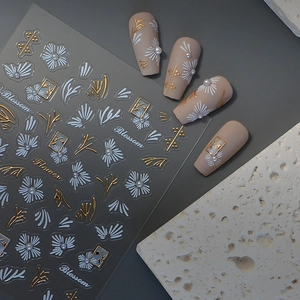 Detailed 3D embossed nail stickers featuring white daisies, gold stems, and pearls