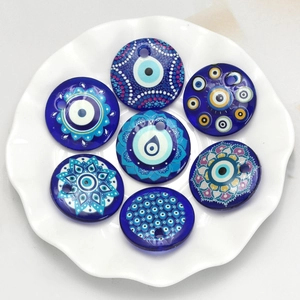 Blue glass evil eye beads arranged on white plate for DIY jewelry making pendants