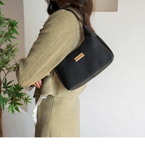 Close-up of black lychee grain leather shoulder bag with decorative gold metal plate