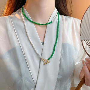 Detail view of emerald ruyi lock necklace with pearls and sand gold koi on model