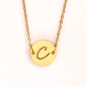 Détail du pendentif pièce dorée avec lettre C évidée et chaîne fine en acier inox