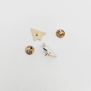 Minimalist gold metal paper plane brooch with white enamel finish and red heart detail