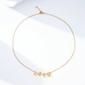 Detailed close-up of golden LOVE letter necklace with link chain and lobster clasp
