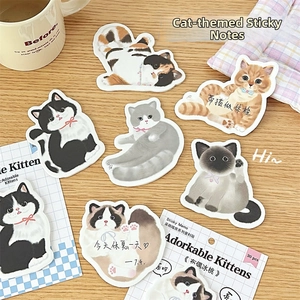 Detail of cute cat shaped sticky notes with various hand-drawn breeds on a wooden desk