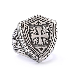 Close-up of vintage silver cross shield ring with retro relief engraving and black finish