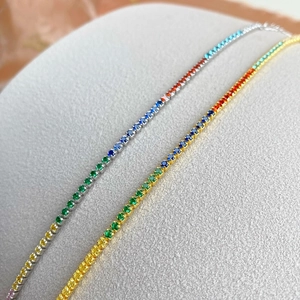 Macro detail of silver and gold tennis bracelets with vibrant rainbow colored gemstones