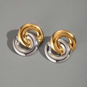 Macro detail of intertwined gold and silver circle earrings in polished titanium steel