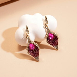 Detailed close-up of vintage gold drop earrings with purple crystals and pink gemstones