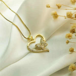 Close-up of gold heart pendant with butterfly detail and cubic zirconia on white silk