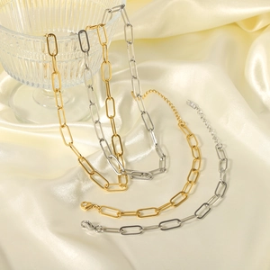 Close-up of gold and silver paperclip necklaces on champagne silk fabric background