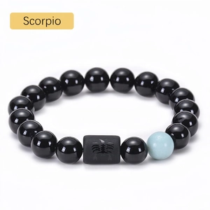 Macro detail of Scorpio beaded bracelet featuring black onyx beads and engraved zodiac charm