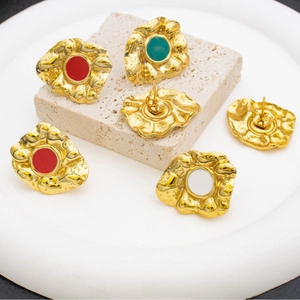 Detail of vintage gold textured earrings with colorful red, green and white enamel centers
