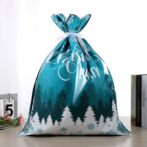Détail du sac cadeau de Noël dégradé bleu avec motifs de flocons et ruban blanc