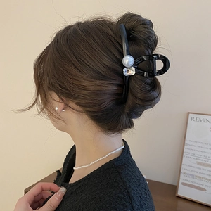 Detail showing an elegant black hair claw with a large pearl and rectangle crystal on hair