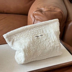 Detailed shot of white floral embroidery and simple wish label on cotton bag
