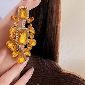 Close-up of luxury long drop earrings with amber stones and pave diamonds on model