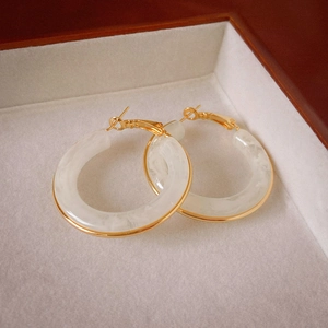 Detailed macro view of gold-plated resin hoop earrings with elegant marble pattern