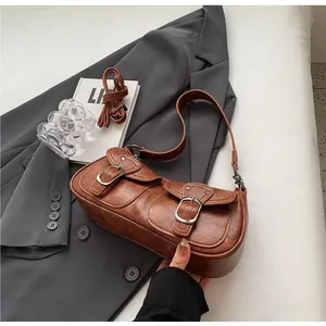 Detail of vintage brown oil-wax leather shoulder bag with functional dual buckled pockets
