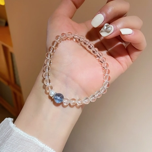 Gros plan d'un bracelet en perles de cristal blanc avec accent bleu et perle au poignet
