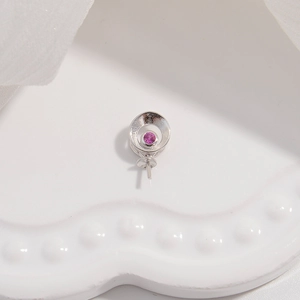 Detail of S925 silver pendant setting featuring a round purple gemstone and zirconia