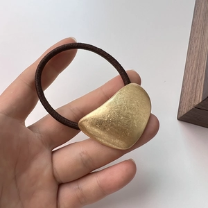 Detail of high-elasticity brown hair tie with irregular matte gold metal accessory