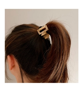 Macro shot of rectangular acetate hair claw in beige marble pattern on a ponytail