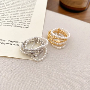Detail of layered gold and silver rings with pearls on a soft fabric and vintage book