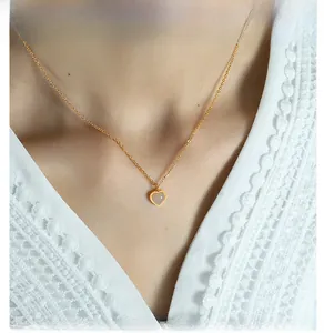 Close-up of a gold heart pendant necklace with red agate on a lace top
